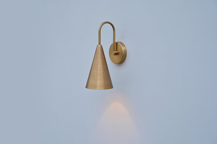 Modern handcrafted brass cone wall sconce with warm tone lighting and minimalist brass wall mount.
