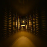 Hobart illuminated perforated cylinder wall sconce casting dramatic warm golden dotted light patterns across a dark wall.