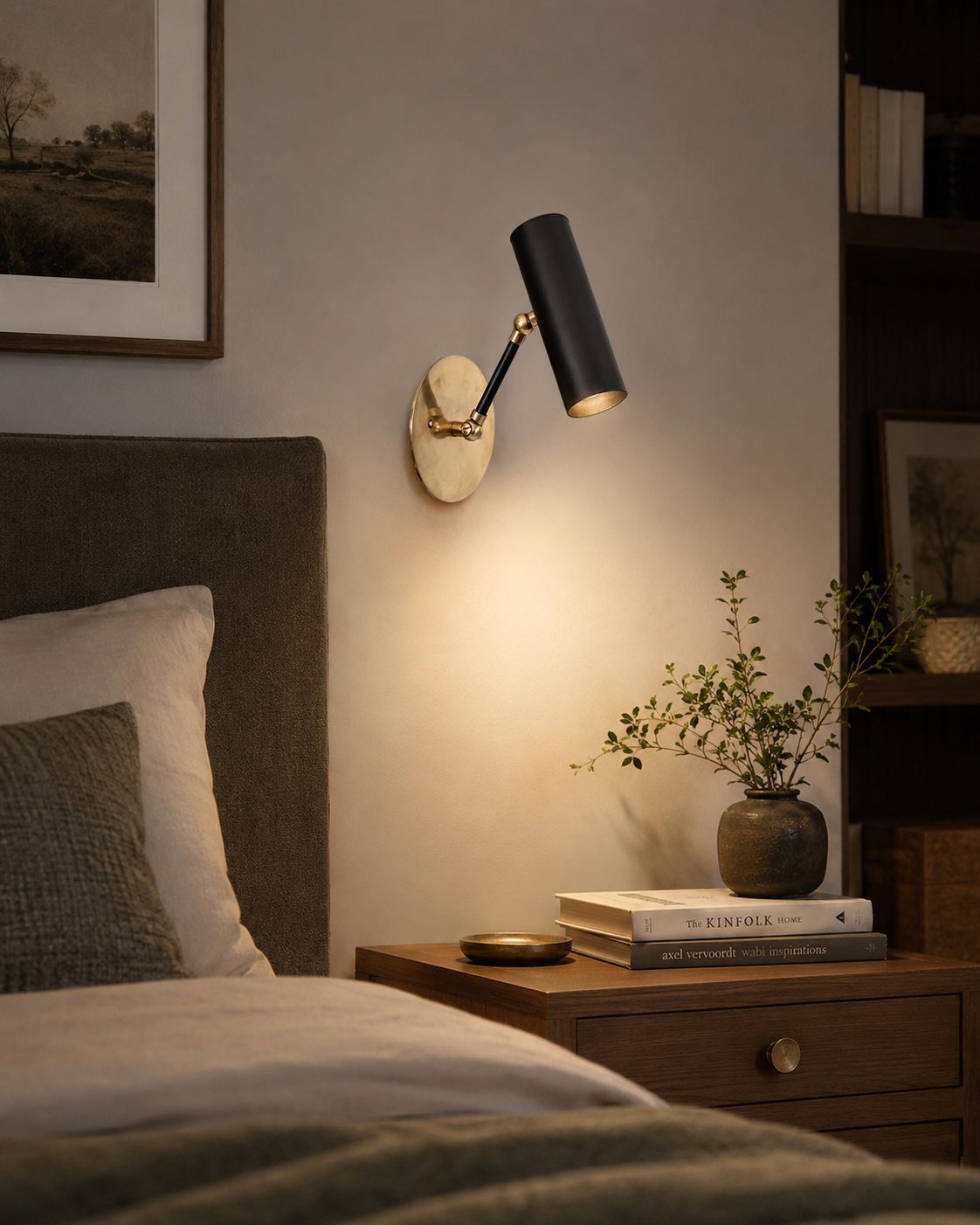 Hudson adjustable cylinder wall sconce installed beside a bed, providing warm directional lighting in a modern minimalist bedroom interior.