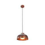 Front view of the Hudson aged copper dome pendant light illuminated with a warm glow, showcasing its handcrafted copper dome shade and rustic verdigris finish.