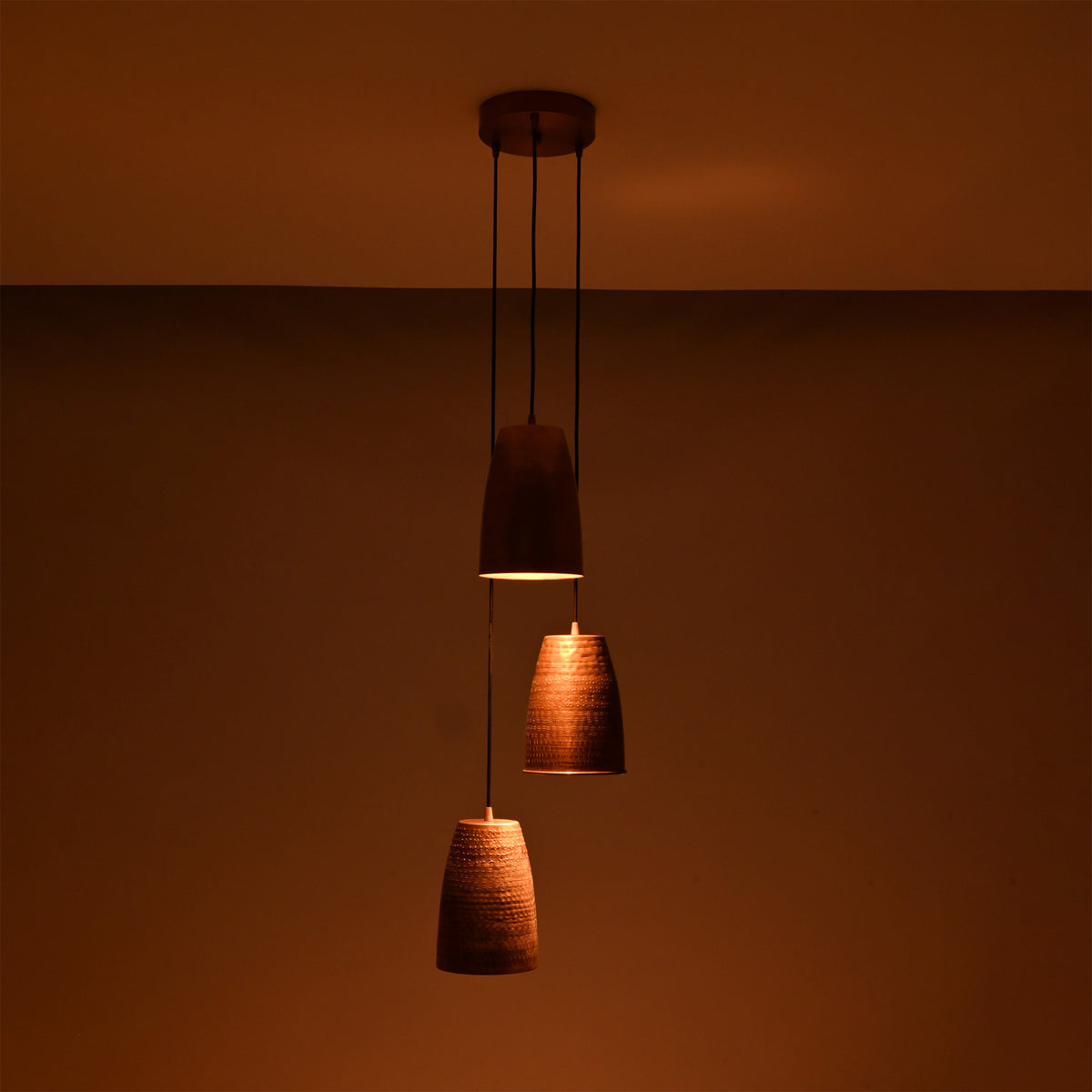 Hudson Cascading Cone Cluster Pendant Light in a dark setting highlighting warm ambient illumination from handcrafted copper cone shades.
