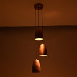 Evening view of the Hudson Cascading Cone Cluster Pendant Light with softly illuminated handcrafted copper cone shades creating a cozy atmosphere.