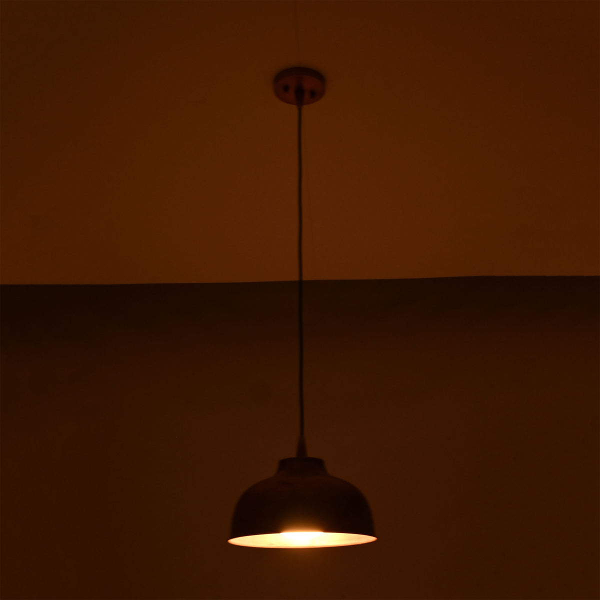 Hudson copper dome pendant light creating a warm ambient lighting effect in a dark interior.