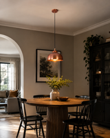 Hudson copper dome pendant light installed above a modern wooden dining table in a contemporary dining room.