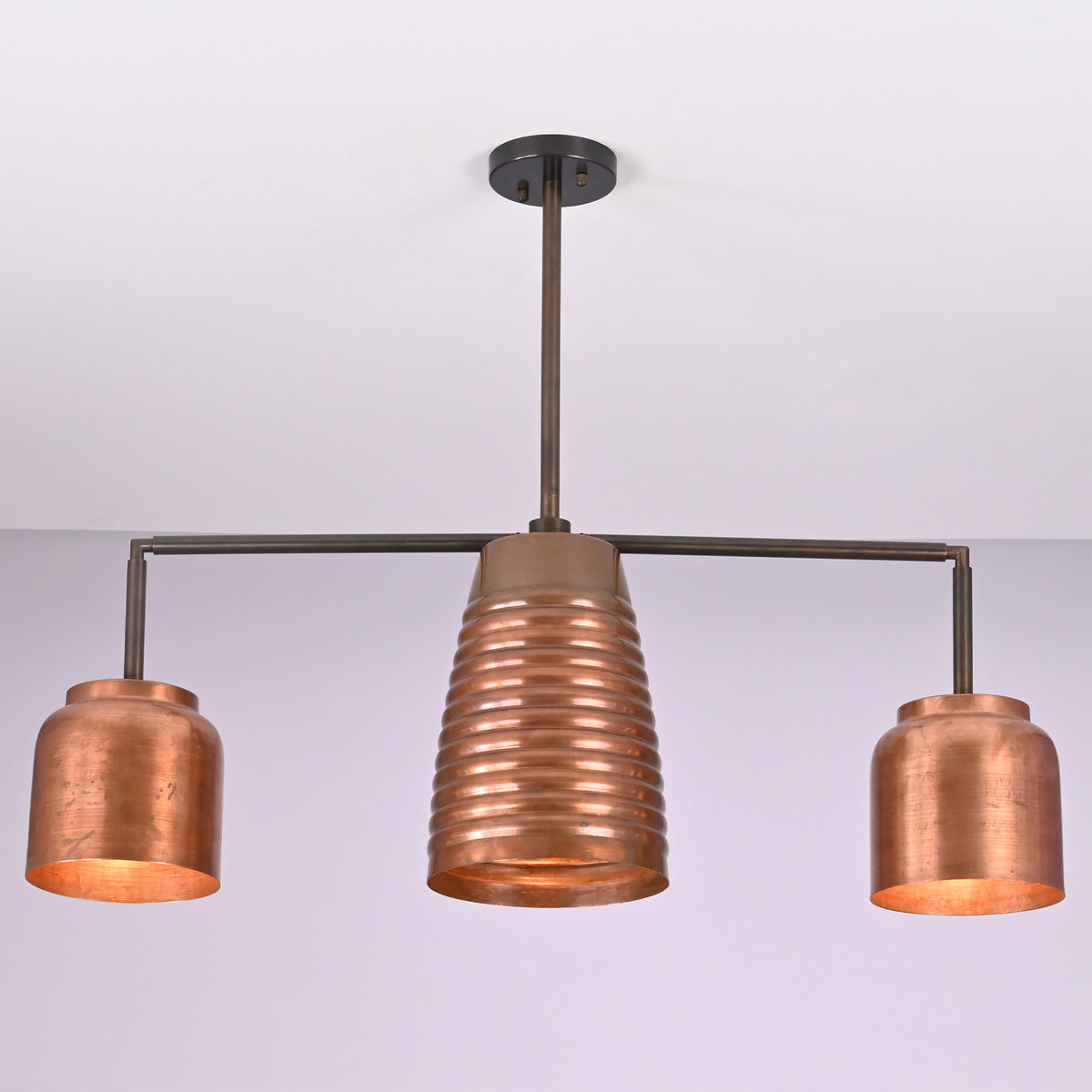Angled view of the Hudson Modern Linear Copper Chandelier highlighting the ribbed center shade and balanced three-light design.