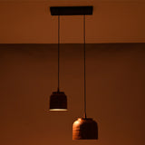 Ambient night view of Hudson hammered copper dual pendant chandelier with staggered pendant shades creating warm focused illumination.