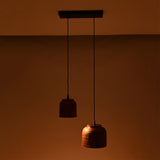 Low-light view of Hudson hammered copper dual pendant chandelier featuring artisan hammered copper shades with warm downward glow.