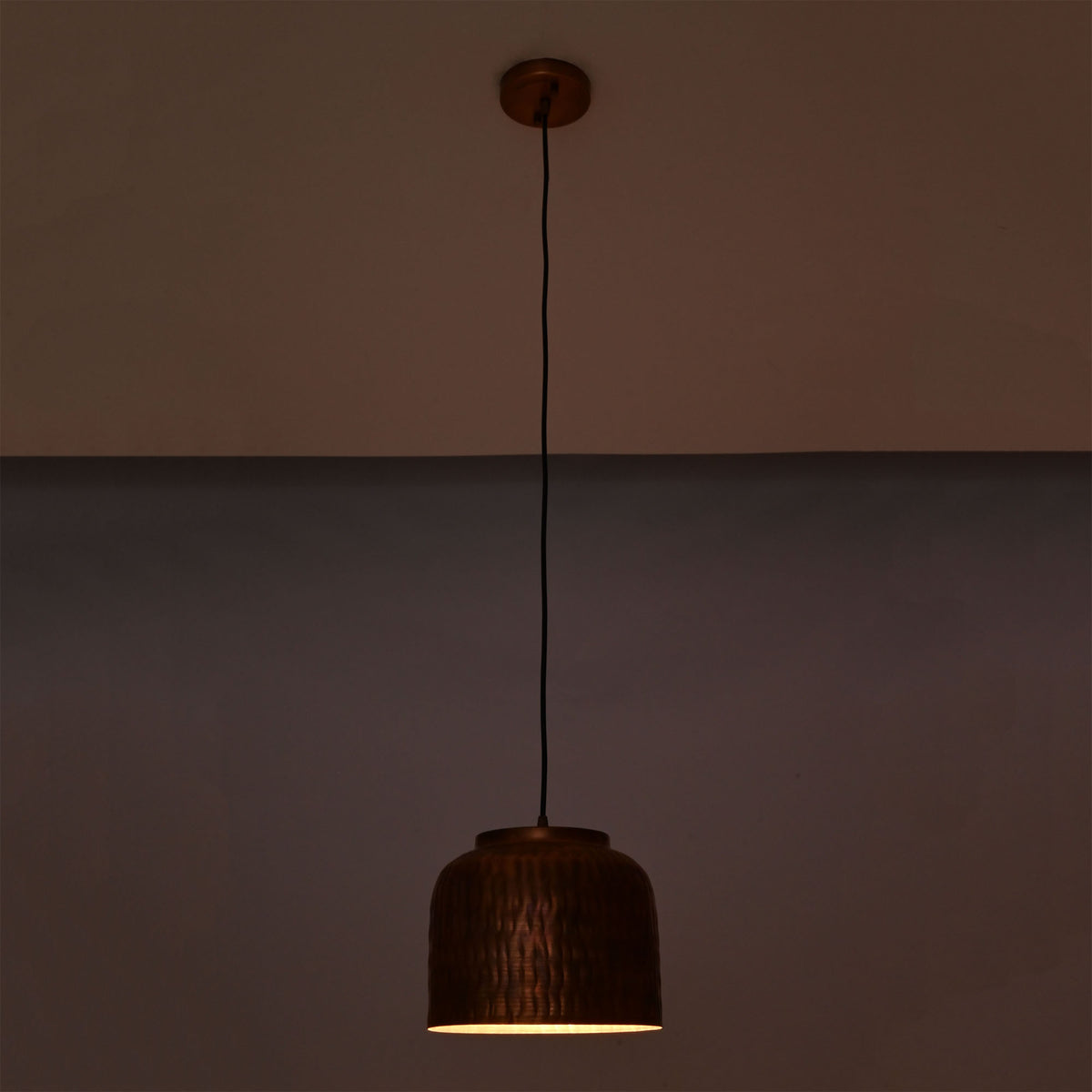 Hudson hammered copper dome pendant light at night emitting warm focused downward illumination