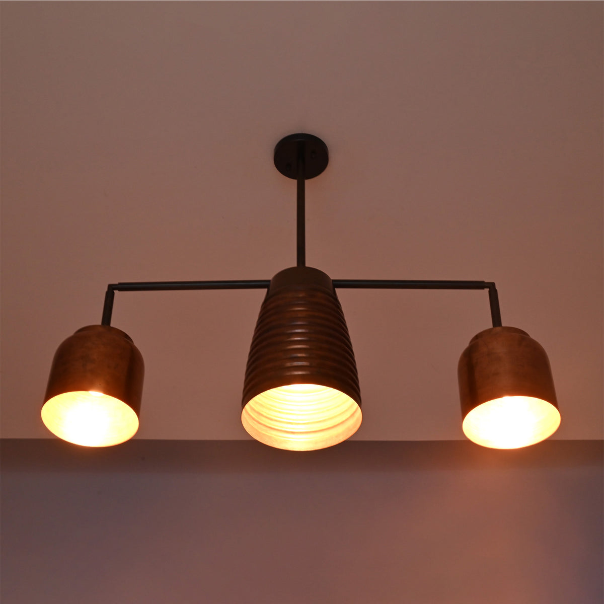 Hudson Modern Linear Three Shade Chandelier producing warm ambient illumination with three downward-facing metal shades.
