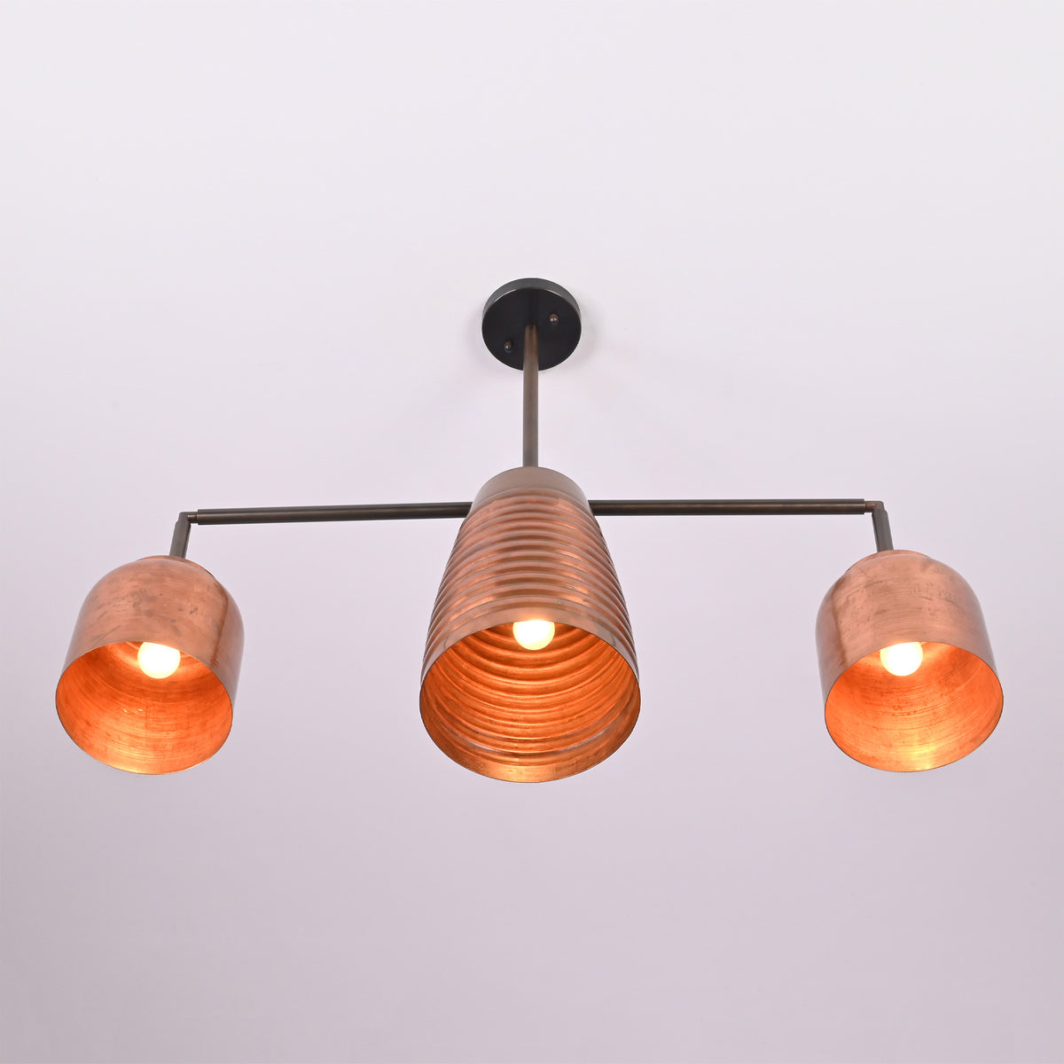 Front view of the Hudson Modern Linear Three Shade Chandelier featuring a ribbed center shade, cylindrical side shades, and warm illuminated bulbs.
