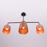 Front view of the Hudson Modern Linear Three Shade Chandelier featuring a ribbed center shade, cylindrical side shades, and warm illuminated bulbs.