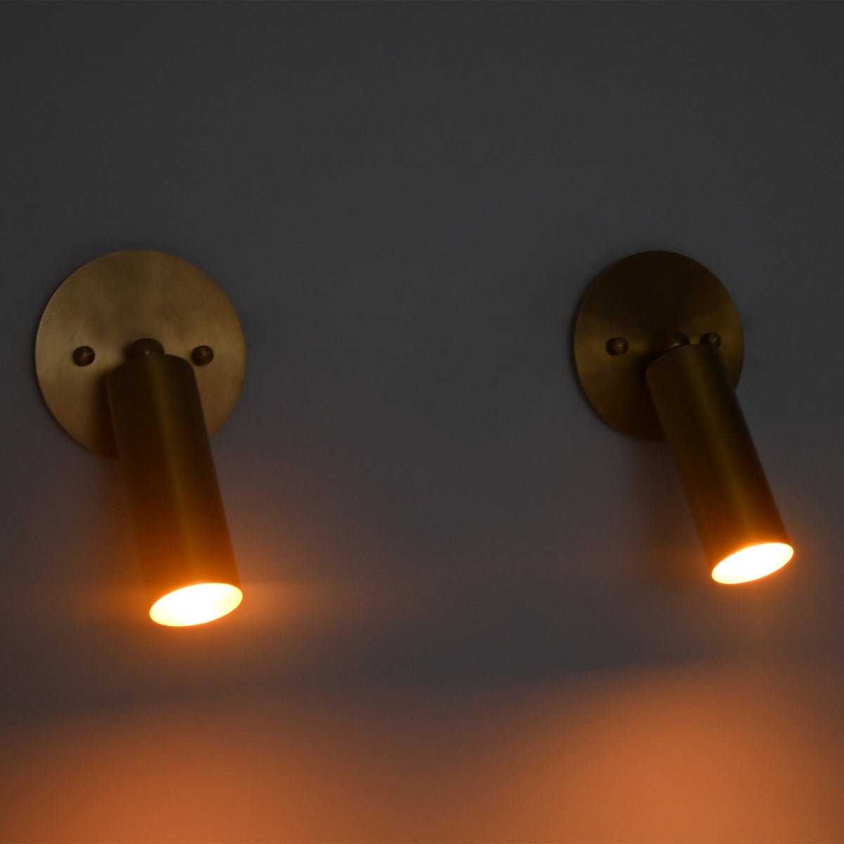 Front-facing view of two Hudson Modern Brass Adjustable Cylinder Wall Sconces providing warm downward illumination with adjustable cylindrical shades.