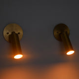 Front-facing view of two Hudson Modern Brass Adjustable Cylinder Wall Sconces providing warm downward illumination with adjustable cylindrical shades.