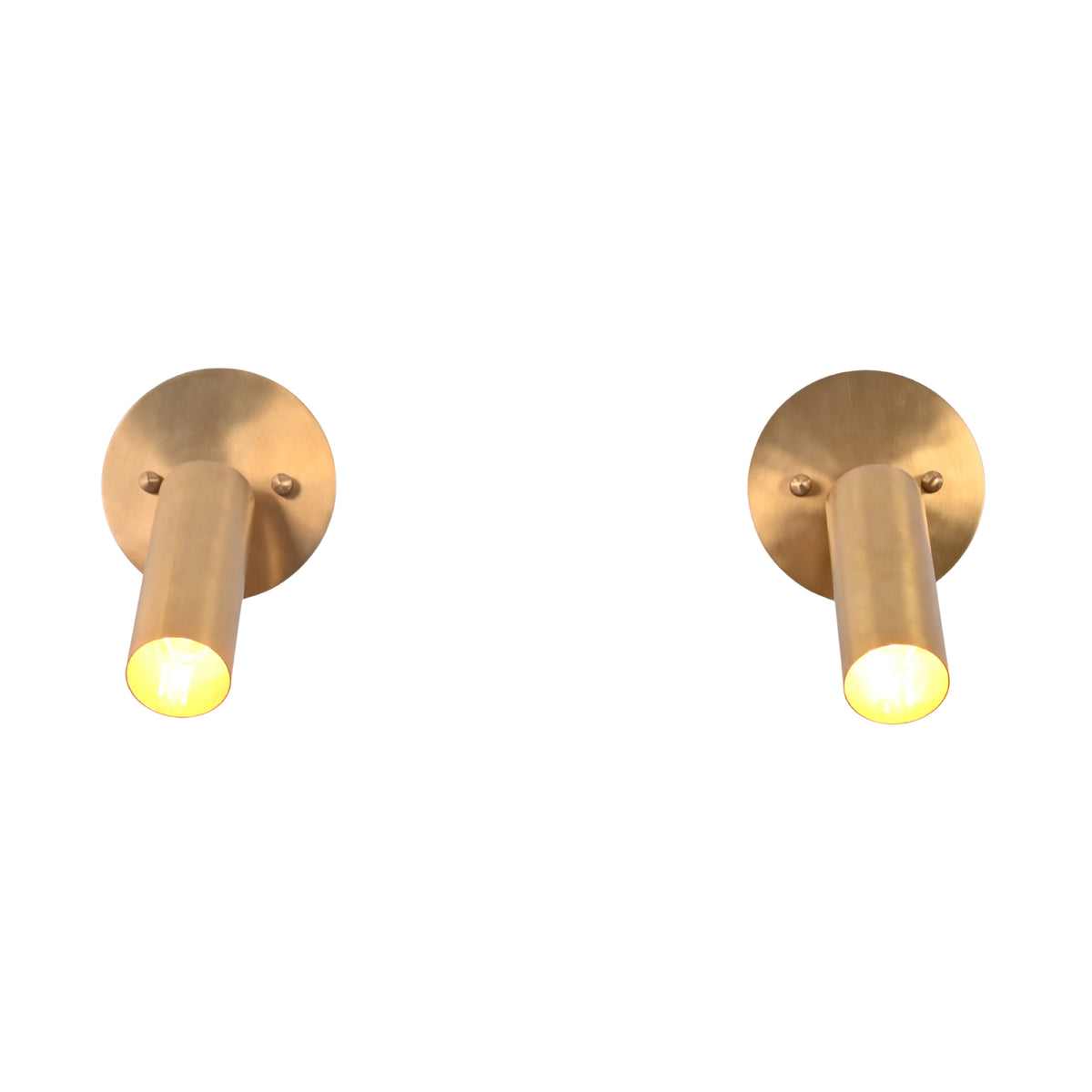 Front view of two Hudson Modern Brass Adjustable Cylinder Wall Sconces illuminated to showcase the focused downward beam and minimalist cylindrical design.
