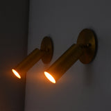 Side angle of the Hudson Modern Brass Adjustable Cylinder Wall Sconce displaying the swivel-mounted cylindrical shade and warm focused directional lighting.