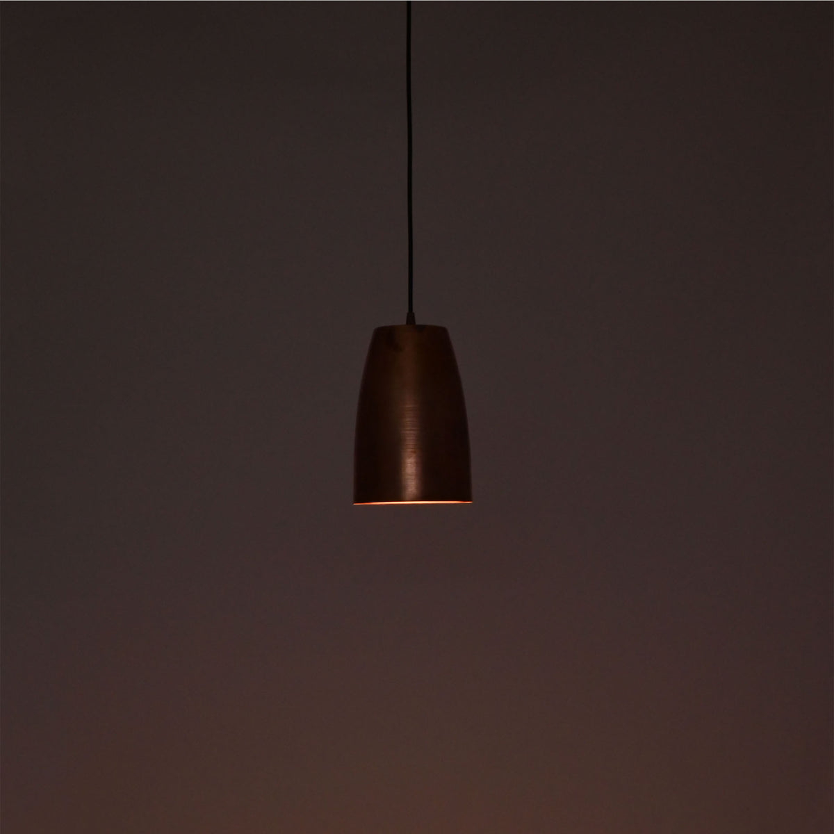Close-up illuminated Hudson brushed copper bell pendant light highlighting handcrafted finish and soft glow