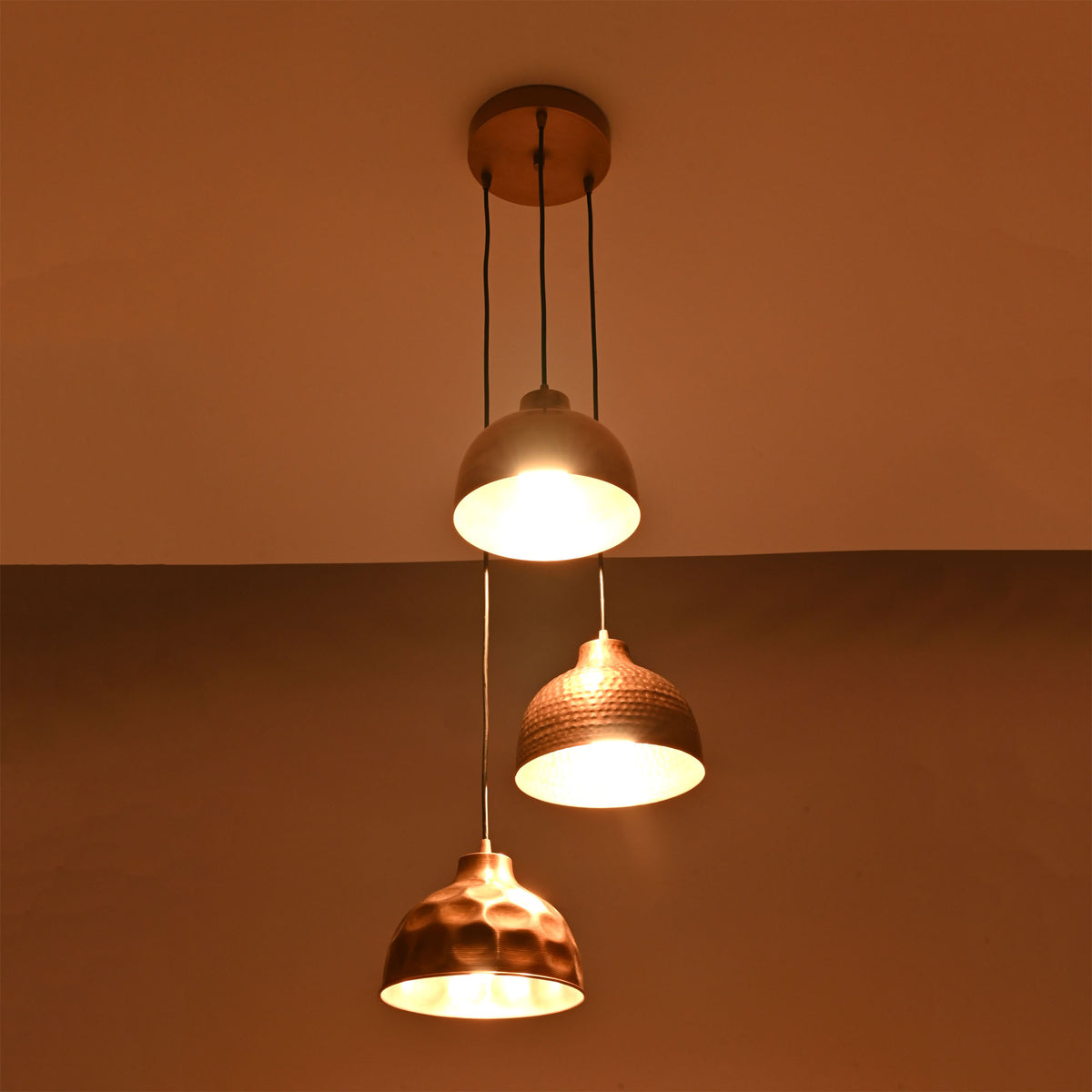 Hudson modern copper three shade cluster pendant light illuminated with warm ambient lighting