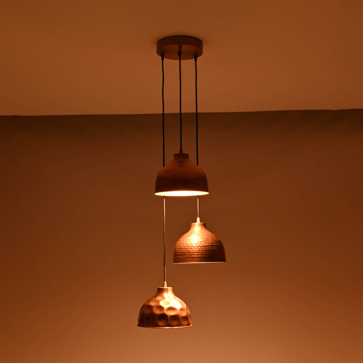 Hudson modern copper three shade cluster pendant light creating warm downward illumination in a dark setting