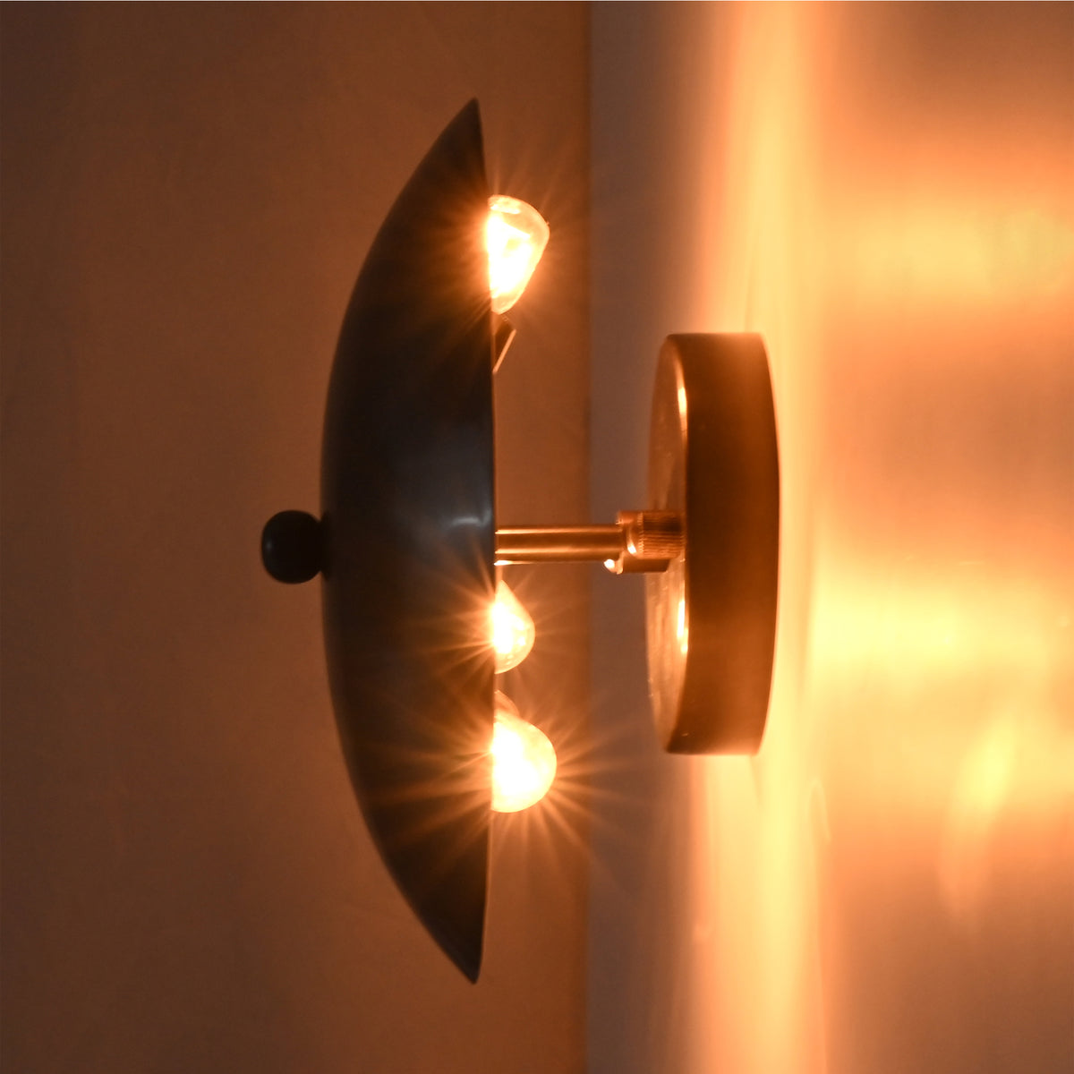 Illuminated side view of the Hudson Modern Dome Wall Sconce showing concealed bulbs creating soft indirect ambient lighting.