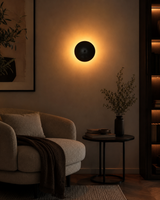 Hudson Modern Dome Wall Sconce installed in a contemporary living room, casting a warm ambient halo against the wall.