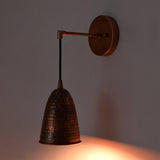 Angled installed view of the Hudson Modern Hammered Copper Cone Wall Sconce featuring a hammered copper cone shade with a warm focused beam, suspended from a sleek cantilever arm.