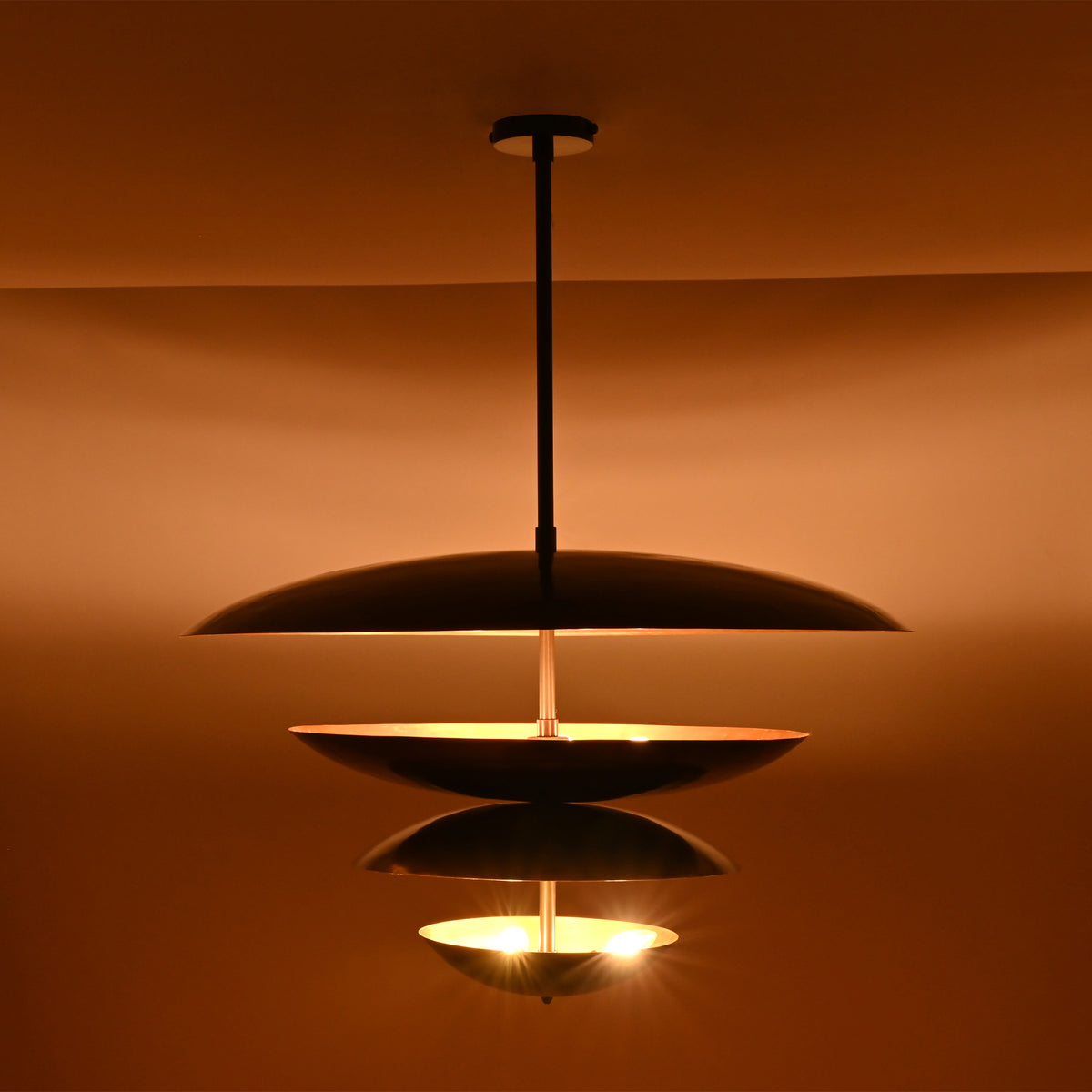 Close-up of the Hudson Modern Layered Disc Chandelier emphasizing the layered disc silhouette, hidden light sources, and warm indirect illumination.