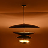 Close-up of the Hudson Modern Layered Disc Chandelier emphasizing the layered disc silhouette, hidden light sources, and warm indirect illumination.