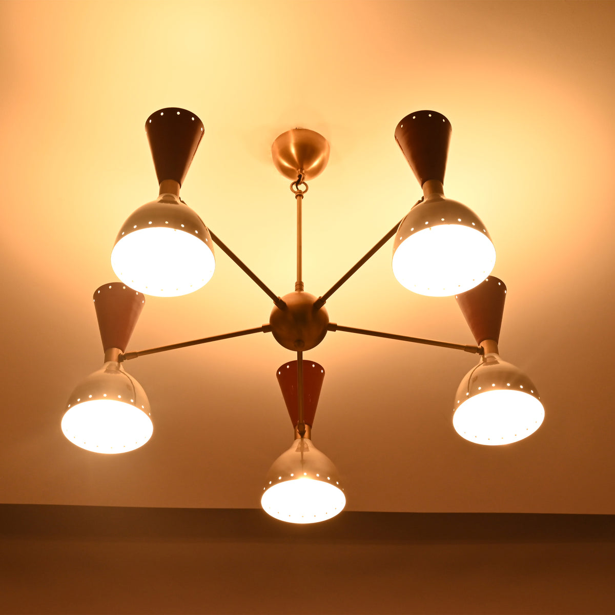 Hudson Modern five-light perforated cone chandelier casting warm ambient ceiling illumination in a Mid-Century Modern interior.