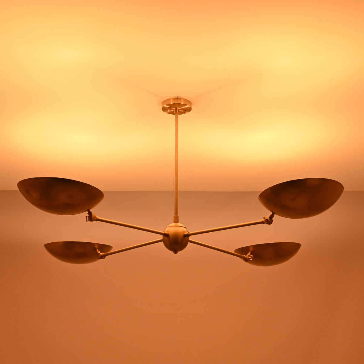 Ambient lighting view of the Hudson Modern Quad Bowl Chandelier creating soft upward illumination with adjustable bowl shades.