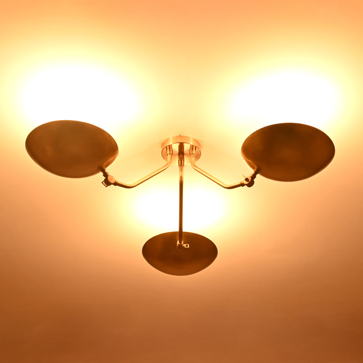 Bottom illuminated view of Hudson brass triple dish chandelier demonstrating soft upward light distribution.