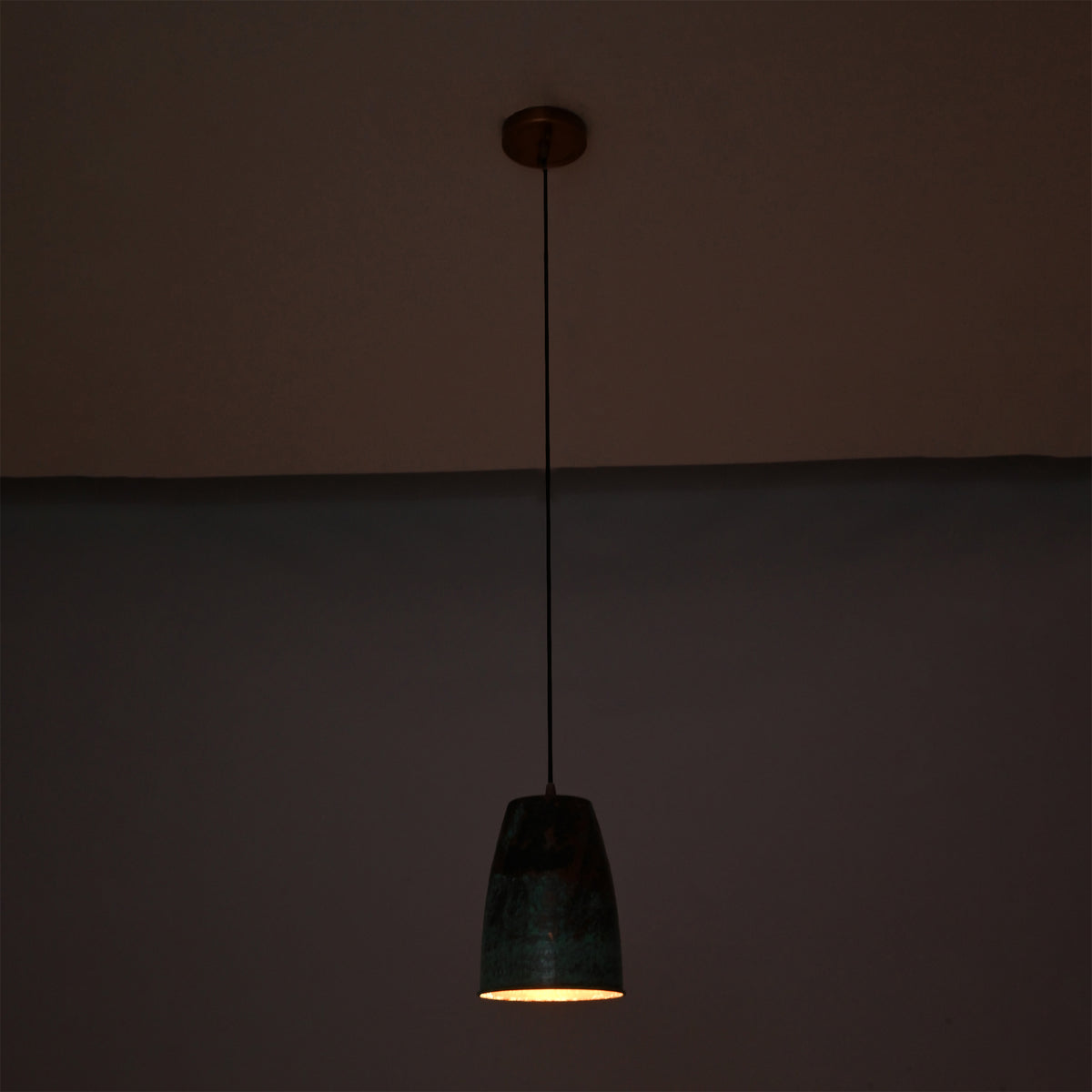 Hudson Verdigris Tapered Pendant Light casting warm focused downward illumination, highlighting its artisan verdigris patina and copper interior.