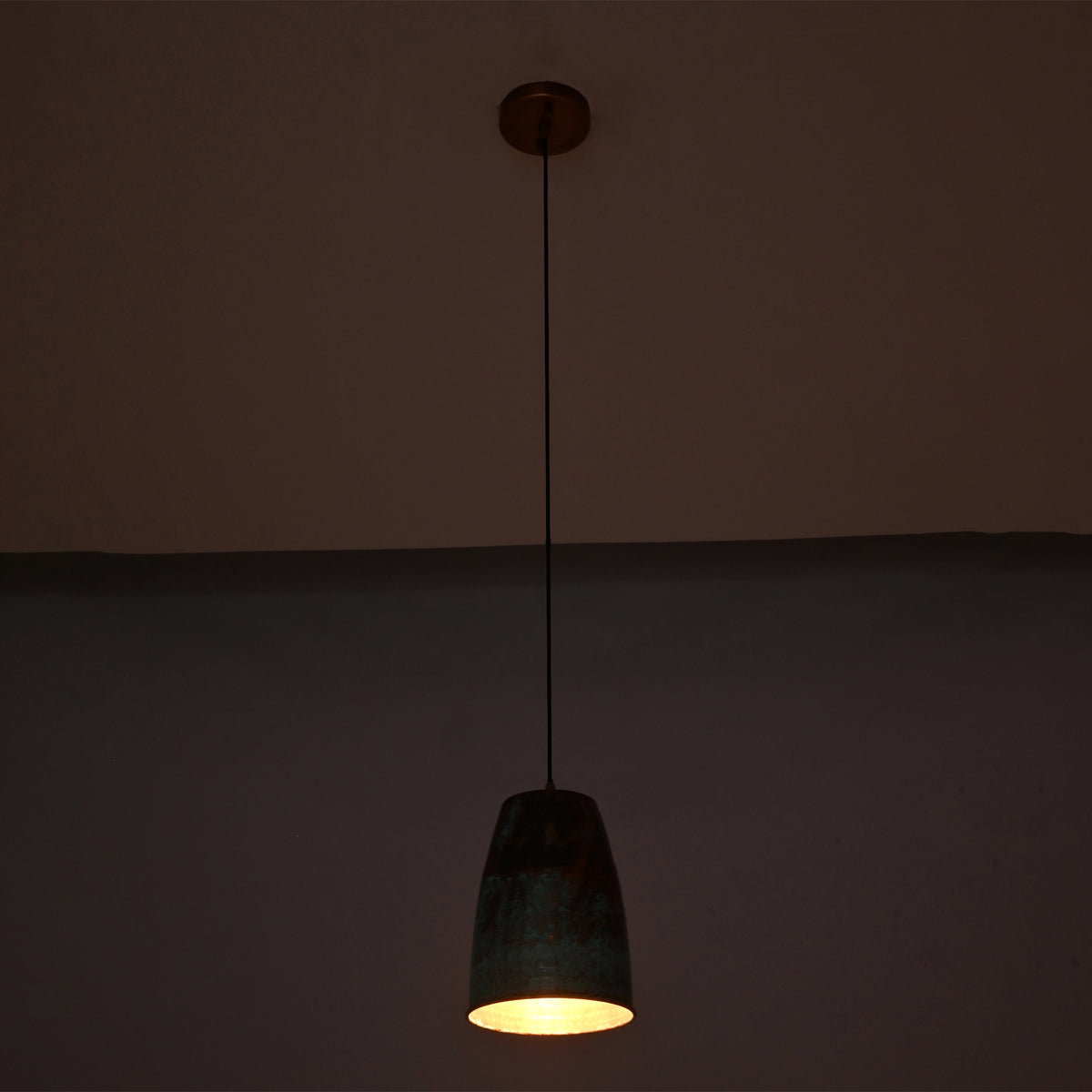 Warm illuminated view of the Hudson Verdigris Tapered Pendant Light featuring a handcrafted tapered shade with an aged verdigris finish and copper-lined interior