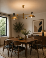 Ibiza 4 light brass-tone balance arm chandelier installed above a wooden dining table in a warm Mid-Century Modern dining room.