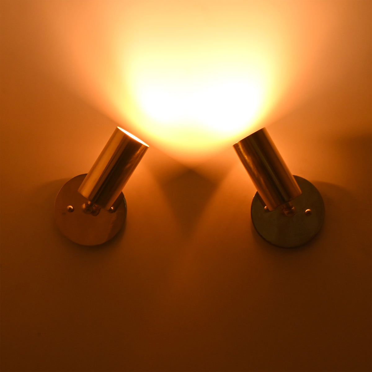 Antique brass adjustable cylinder wall sconce casting a focused warm directional beam, perfect for accent lighting and artwork illumination.