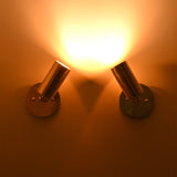 Antique brass adjustable cylinder wall sconce casting a focused warm directional beam, perfect for accent lighting and artwork illumination.