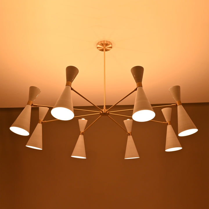 Warmly lit brass chandelier with white cone shades, glowing softly against a beige ceiling in a modern interior setting