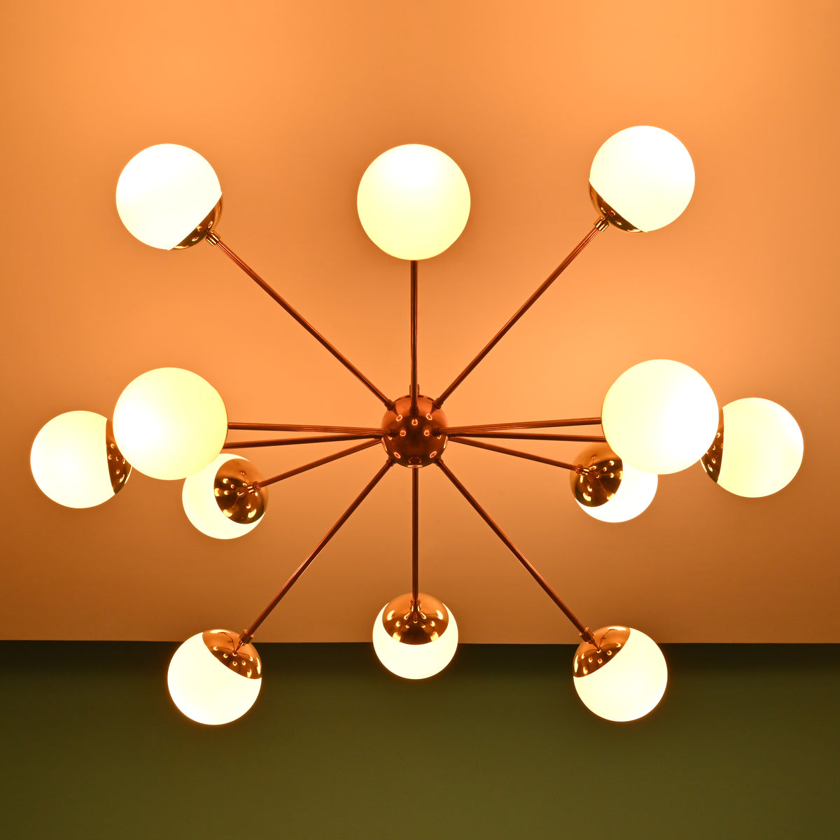 Bottom view of an illuminated brass Sputnik chandelier with frosted globe shades casting warm ambient light.