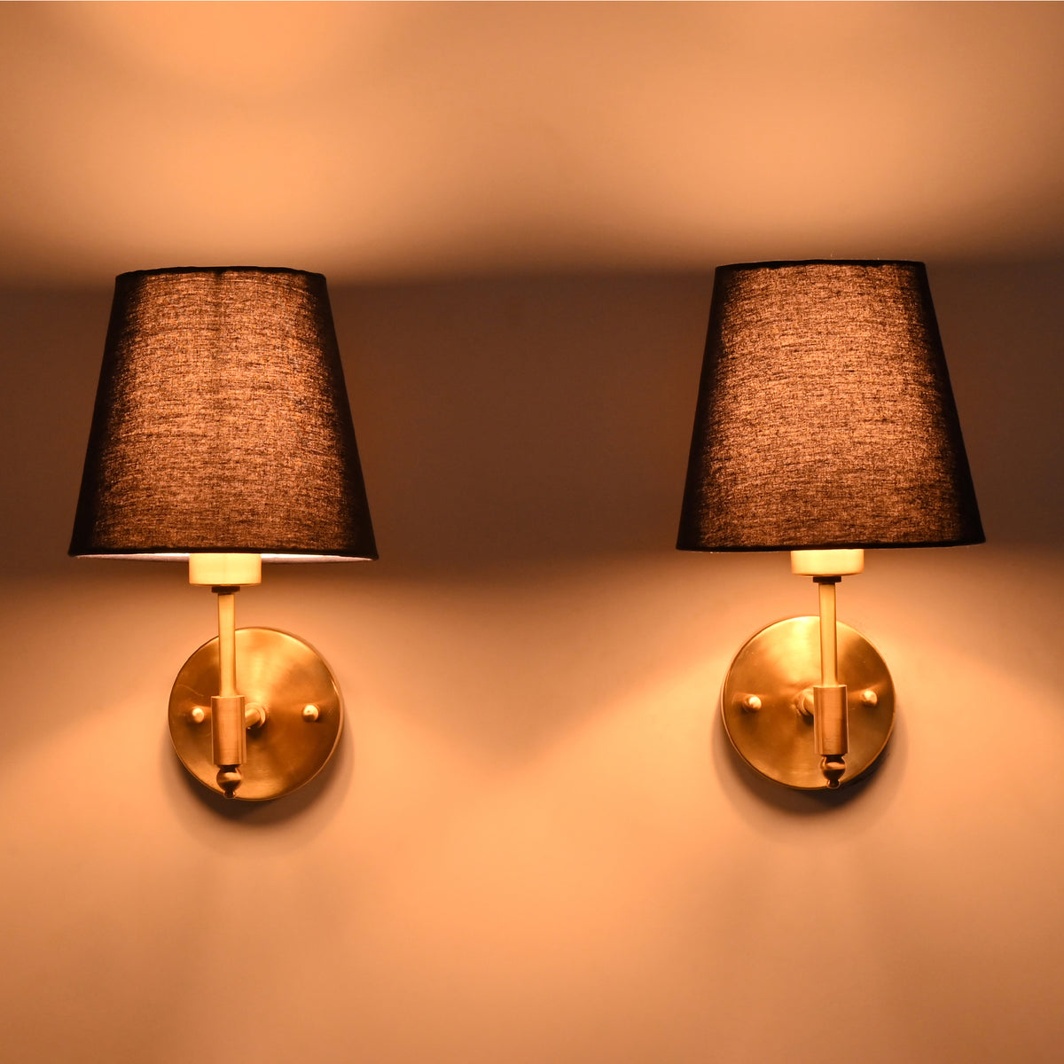 Antique brass wall sconce illuminated with a rich blue tapered fabric shade, casting a warm ambient glow against the wall.