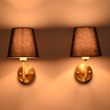 Antique brass wall sconce illuminated with a rich blue tapered fabric shade, casting a warm ambient glow against the wall.