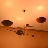 Multicolor brass chandelier glowing warmly under ceiling light, displaying ambient lighting and artistic color blend.
