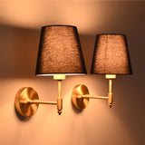 Pair of illuminated antique brass wall sconces with rich blue tapered fabric shades, creating warm ambient lighting for modern classic interiors.