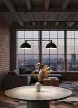 Brass double pendant with green dome shades hanging above a round table in an industrial loft living space at dusk.