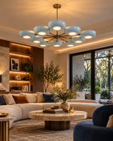 Lecce 10-light Mid-Century Modern chandelier featuring light-blue bowl shades above a cream sectional sofa, round stone coffee table, and warm contemporary living room decor.
