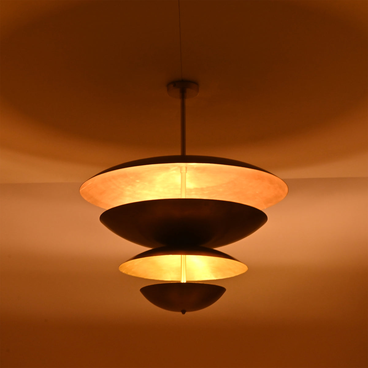 Night view of the Lior Modern Tiered Disc Chandelier producing soft diffused illumination through its floating tiered disc construction