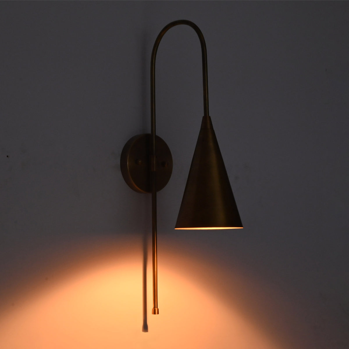 Angled view of Liora Cone Loop Wall Sconce highlighting the cone shade and warm wall illumination.