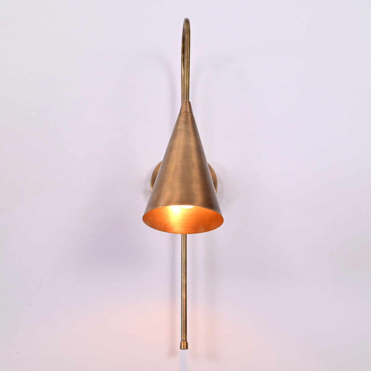 Liora Cone Loop Wall Sconce glowing warmly from the front with focused downward light effect.