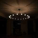 Lucca 18 light starburst Sputnik chandelier shown illuminated with exposed globe bulbs and radial metal arms.