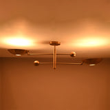 Warm illuminated detail of the Luna Modern Double Bowl Chandelier highlighting its sculptural brass bowl shades and balanced linear design