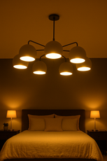 Matte black chandelier with seven dome-shaped lights casting a warm glow over a minimalist bedroom setting