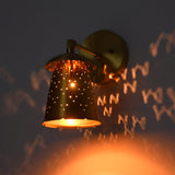 Close angled view of perforated bell shade creating star-like glow and decorative wall patterns.